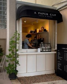 a small coffee shop on the side of a building with plants growing out of it