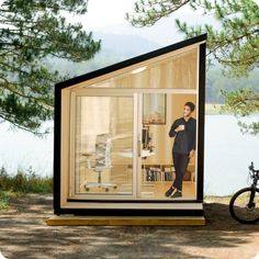 a person standing in front of a glass house with a bicycle parked next to it