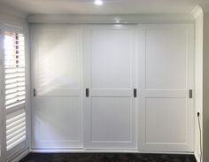 an empty room with white closet doors and black carpet