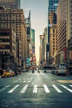 an empty city street with tall buildings and people walking on the sidewalk in the distance