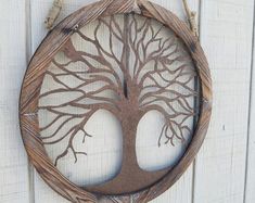 a wooden circle with a tree cut out of it hanging on the side of a building