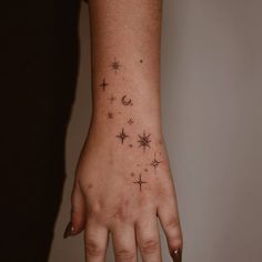 a woman's hand with stars and moon tattoos on it