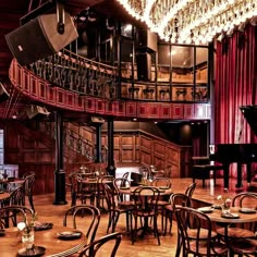 an empty restaurant with chandeliers and tables in front of a piano on the wall