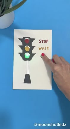 a hand pointing at a stop light card