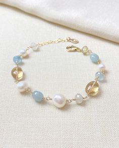 This artisan-crafted bracelet contains beautiful warm and cool-colored gemstones paired with white pearls for an elegant fall look. Each hand-picked gemstone and pearl is meticulously wire-wrapped in gold fill for a timeless look. This piece looks great on its own, but easily stacks with other favorite bracelets. Bracelet length:  7 inches plus 1 inch extender MATERIALS ~ Champagne quartz ~ Golden rutilated quartz ~ Aquamarine ~ Cultured freshwater pearls ~ Gold fill GIFTING ~ Jewelry gift box included. ~ I am happy to ship directly to the recipient.  Enter their address during checkout. ~ If you would like a gift note included in the package, please leave the text of the note in the "Add a note to Marsh Creek Jewelry" message box at checkout. FREE SHIPPING ~ Orders ship within 2 business Wire Wrapped Gemstone Jewelry, Wire Clasp, Pearl Beaded Bracelet, Golden Quartz, Ladies Bracelet, Golden Rutilated Quartz, Colored Gemstones, Artisan Bracelets, Elegant Fall