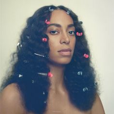 a woman with long black hair has pink and blue pins pinned to her face as if she is listening to music