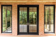 two black double doors with glass on brick wall and wood flooring in front of them