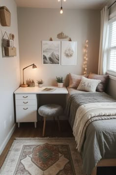 a small bedroom with a bed, desk and chair in front of a window that has two pictures on the wall above it