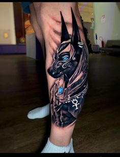 a man's leg with tattoos on it and an image of the egyptian god