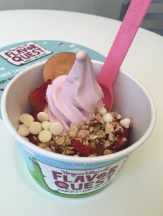 an ice cream sundae with strawberries and nuts in a cup on a table