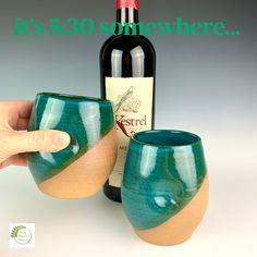 a hand holding a wine glass next to a bottle