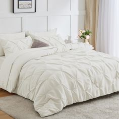 a bed with white comforter and pillows in a room