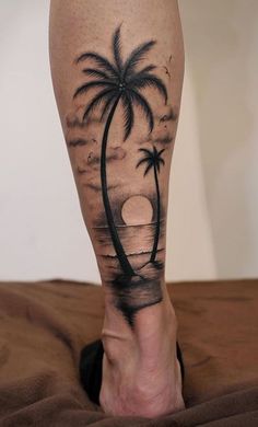 a person's leg with a palm tree and sunset on the beach tattoo design