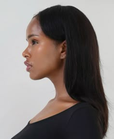 a woman with long black hair is looking off to the side while wearing a black shirt