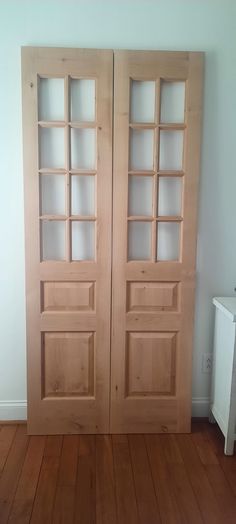 an empty room with two wooden doors on the wall and wood flooring in front of it