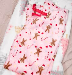 a baby's pink blanket with gingerbreads on it and a red ribbon