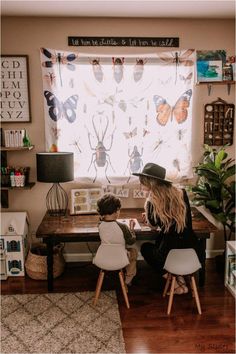 a woman and child sitting at a table in front of a window with butterflies on it