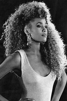 a black and white photo of a woman with long curly hair wearing a tank top