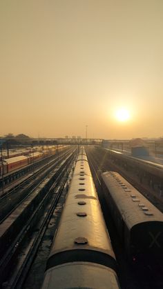 several trains are parked on the tracks at sunset