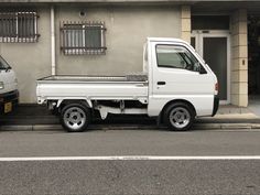 a white truck parked in front of a building next to a silver car on the street