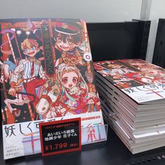 a stack of anime books sitting on top of a table next to another pile of magazines