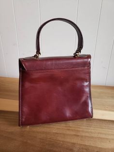 This is a vintage, Brahmin, oxblood leather, top handled purse, with a shoulder strap. It has a few marks on the leather and a scratch as well as a very small hole on the interior flap. You can see this in the images. The price reflects this. This was made in the USA. The measurements are as follows:10.5 inches across x 9.25 inches in height x 3.74 inches at the widest part. The strap measures 48 inches, including the hardware and can be adjusted to be made smaller. The handle measures 11.5 inch Formal Burgundy Satchel With Handle Drop, Classic Burgundy Satchel With Leather Lining, Formal Handheld Burgundy Satchel, Formal Retro Burgundy Bag, Vintage Red Shoulder Bag For Business, Retro Burgundy Formal Bags, Red Vintage Shoulder Bag For Business, Retro Burgundy Formal Bag, Vintage Top Handle Shoulder Bag With Leather Lining