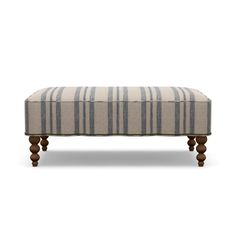 an upholstered bench with wooden legs and striped fabric on the top, against a white background