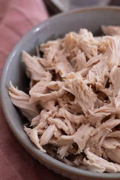 a bowl filled with shredded meat sitting on top of a pink cloth covered tablecloth