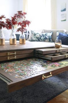 a coffee table with puzzle pieces on it and flowers in vases sitting on top