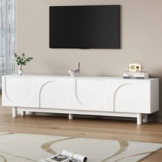 a cat sitting on top of a white cabinet in front of a flat screen tv