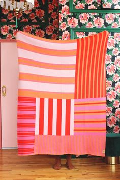 a woman standing in front of a pink and orange blanket