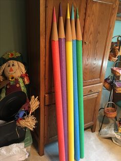 several colored pencils lined up in front of a wooden cabinet and stuffed toy on the floor