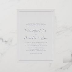 a white and gray wedding card on top of a marble surface with the wording