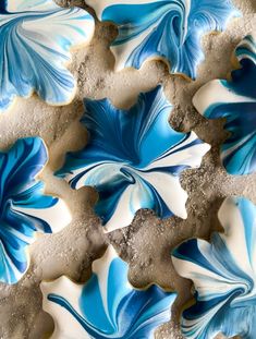 some blue and white cookies are on a plate with icing in the shape of leaves