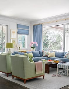 a living room filled with lots of furniture next to a window covered in blue curtains