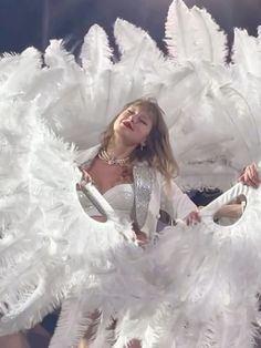 the woman is dressed in white and posing with her wings