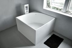 a white bath tub sitting in a bathroom next to a black and white rug on the floor