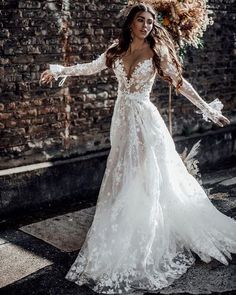 a woman in a wedding dress standing on the street with her arms out and hands outstretched