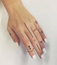 a woman's hand with four different tattoos on her fingers and one has an arrow