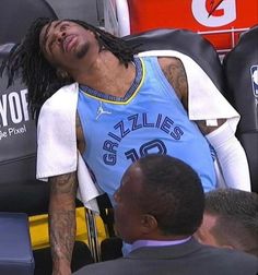 a man laying on top of a chair next to another person wearing a blue shirt