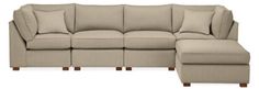 a beige sectional couch with pillows on it and a footstool next to it