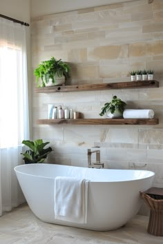 a white bath tub sitting in a bathroom next to two shelves with plants on them