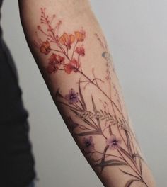 a woman's arm with flowers and leaves painted on the back of her arm