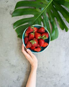 a person holding a bowl full of strawberries