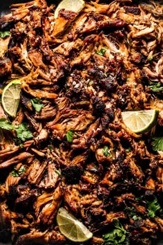 an overhead shot of shredded meat with limes and cilantro on the side