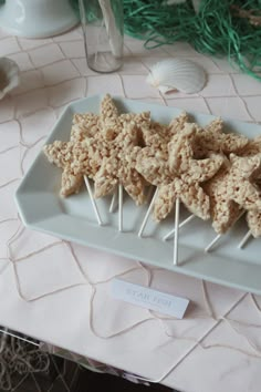 rice krispy treats are arranged on a white plate with toothpicks in the middle