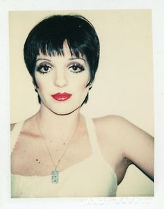 an old photo of a woman with short hair and green eyeshade, wearing a white tank top