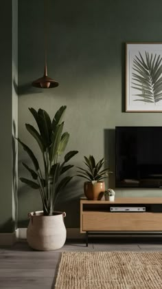 a living room with green walls and plants on the table in front of the tv