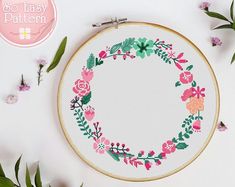 a cross - stitch pattern with flowers and leaves on it, next to the embroidery hoop