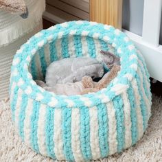 a blue and white knitted pet bed on the floor next to a radiator